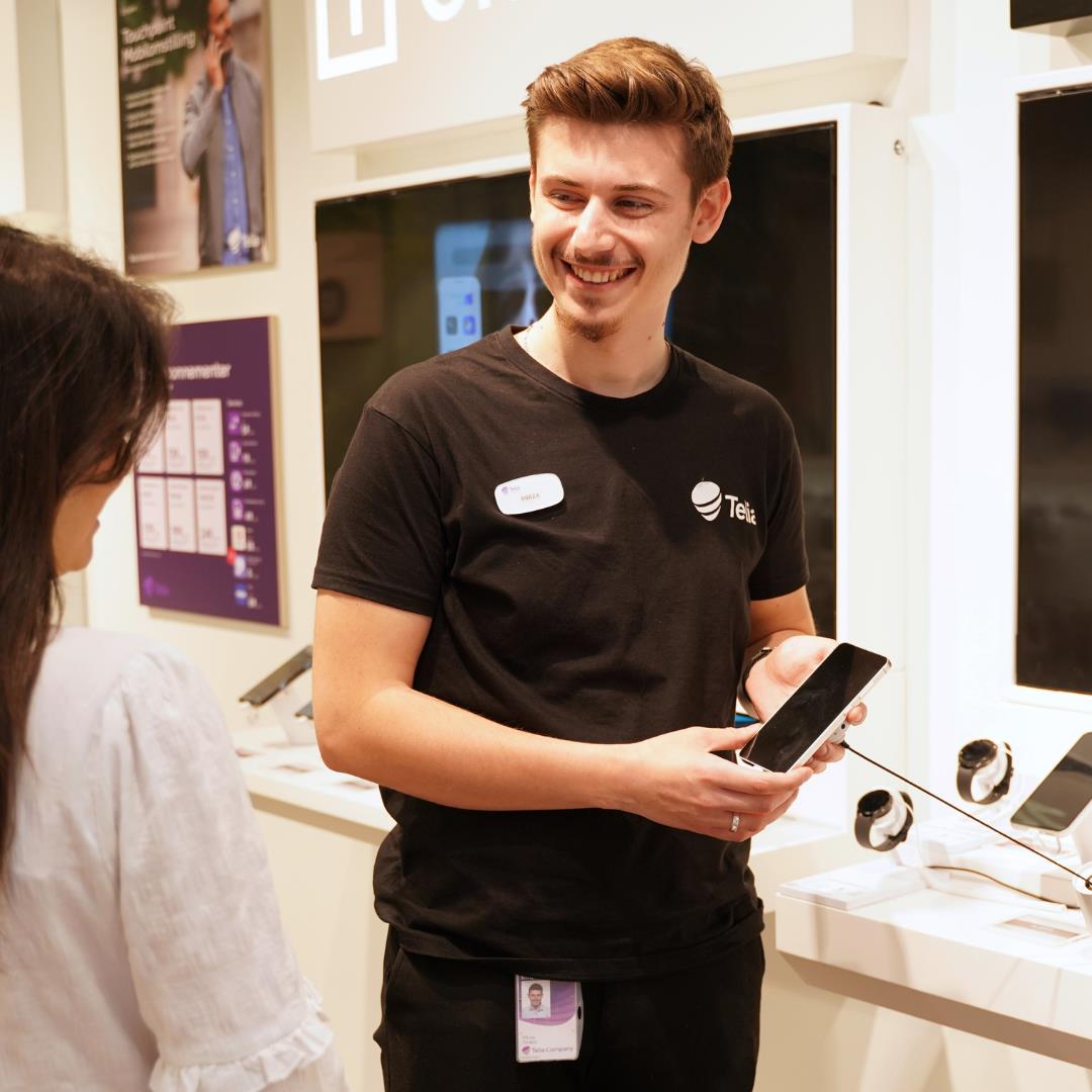 Medarbejder fra Telia i Randers Storcenter viser en mobiltelefon til en kunde.